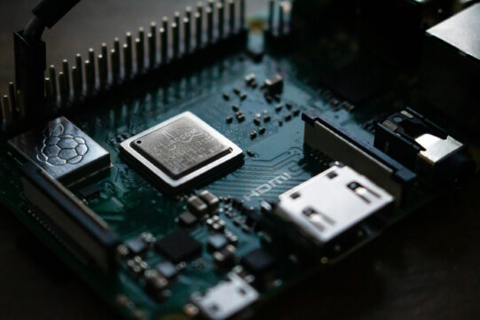 Raspberry Pi Platine mit sichtbarem Prozessor, HDMI-Anschluss und GPIO-Pins, beleuchtet. Ideal für Elektronikprojekte.