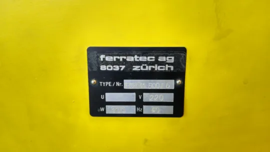Schwarzes Typenschild von Ferratec AG auf gelbem Hintergrund, zeigt Modell Ferra 500/6, Spannung 220V, Leistung 300W, 50Hz.