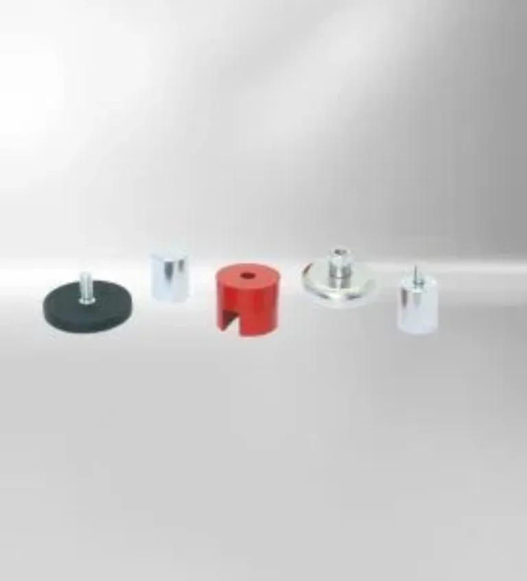Fünf verschiedene Abstandhalter aus Metall und Kunststoff auf grauem Hintergrund, inklusive rotem und silbernem Modell.